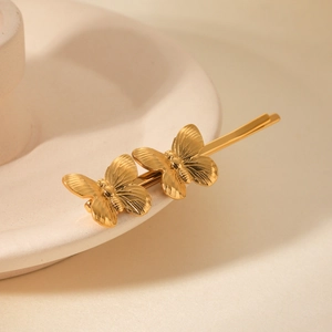 Détail d'une pince à cheveux papillon en or 18 carats avec des textures fines et métal
