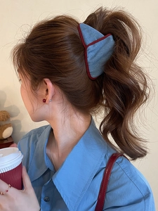 Close-up of a blue denim triangle hair claw clip worn on a high ponytail by a model