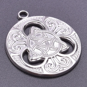 Detailed macro view of silver Celtic knot pendant with scrollwork relief carving