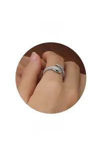 Détail macro d'une bague serpent argentée avec écailles et pierre verte sertie