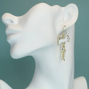 Detail of cute white cat and gold fishbone earring on a white mannequin head display