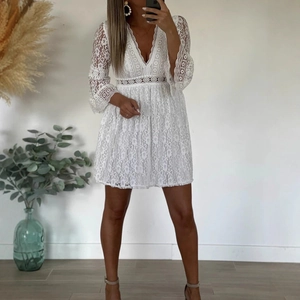 Detailed view of white floral lace fabric with hollow out texture and elegant flared sleeves