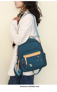 Detail of blue canvas backpack featuring colorful embroidery of rabbits and pumpkins
