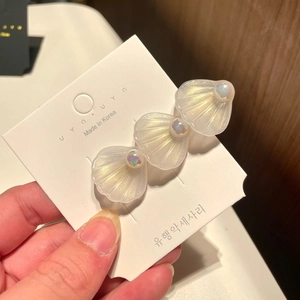Detailed view of three iridescent pearl white shell hair clips with small beads on card