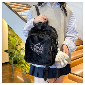 Detail of black plush backpack with white heart embroidery and cartoon charm