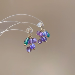 Detailed close-up of colorful floral stud earrings with purple beads and gold metal accents