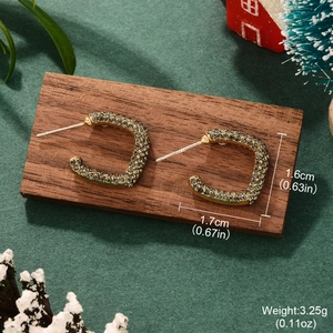 Detailed view of gold C-shaped earrings with dark rhinestones in Christmas setting