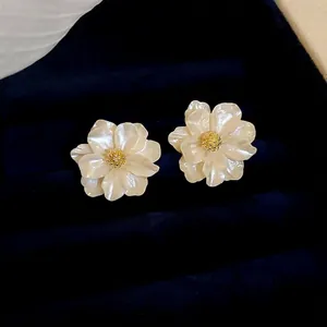 Elegant resin camellia flower stud earrings with golden pistils on dark velvet background