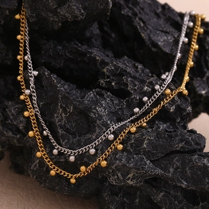 Detail of 18K gold and silver necklaces with bead pendants on black rock backdrop