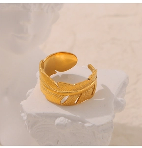 Nahaufnahme eines goldenen verstellbaren Rings in Federform auf weißem Sockel