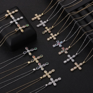 Macro shot of cross pendants with white, colorful and blue-green zircons on black background