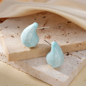 Elegant light blue marble teardrop earrings on a beige stone and silk background