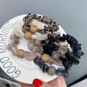 Close-up of four scrunchies with rhinestones in leopard, beige, brown, and black colors