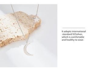 Detail of S925 sterling silver moon and star necklace on natural stone backdrop