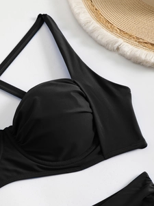 Detail of black bikini top with pleated cups and supportive structure on a beach background