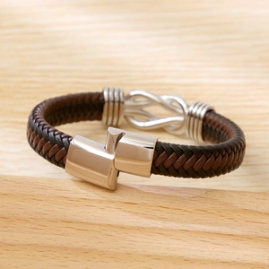 Brown braided leather bracelet with silver infinity charm on a natural wood background