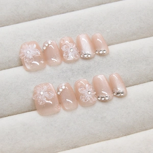 Handmade cat eye press-on nails with 3D floral designs and crystals on a velvet tray