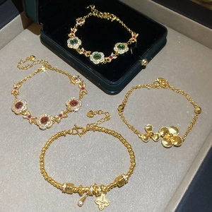 Close-up of 24K gold plated bracelets featuring floral patterns and gemstone charms
