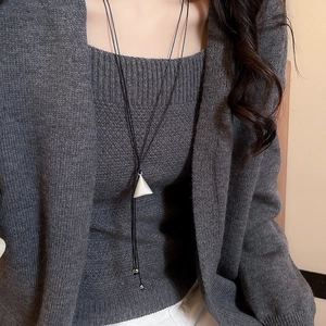 Close-up of a silver triangle pendant on a black adjustable leather cord over a grey sweater