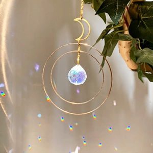 Detail of crystal suncatcher moon frame creating rainbow light spots on wall