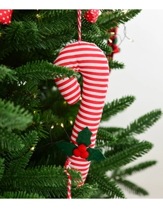 Detail of red and white striped candy cane ornament with holly berries on a Christmas tree