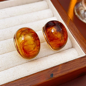 Macro view of vintage amber resin round earrings in a wooden jewelry display box
