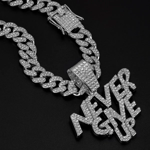 Macro detail of iced-out Never Give Up letter pendant on silver Cuban link chain