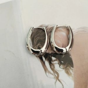Macro shot of silver U-shaped earrings with mirror-polished finish on a magazine page