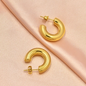 Minimalist gold hollow C-shaped hoop earrings displayed on elegant pink satin fabric
