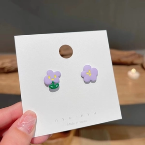 Detail of asymmetric purple flower earrings with green leaf and yellow center