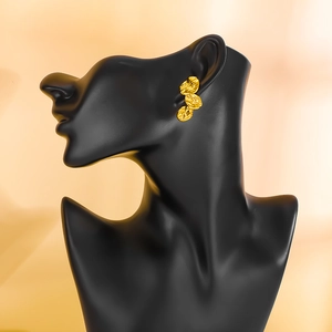 Detail view of gold hammered petal earrings on a black mannequin with a soft warm background