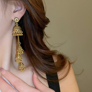 Macro side view of ethnic gold Jhumka tassel earrings worn by a model