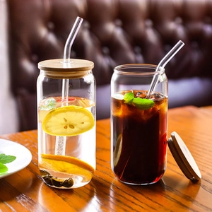 Detail of clear glass can cups with bamboo lids and glass straws in a cozy home setting