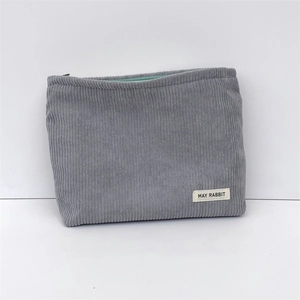 Detail view of grey corduroy makeup bag with mint green zipper and branded label