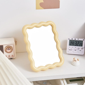 Modern wavy-edged beige desktop makeup mirror on a minimalist white table surface