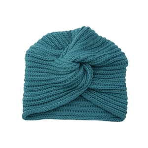 Detailed knit texture of a dark teal bohemian turban hat with crisscross twist design