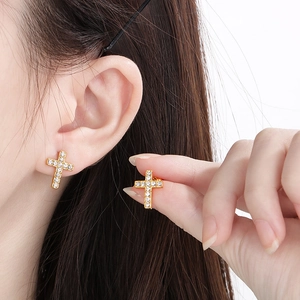 Close-up of golden stainless steel cross earrings with sparkling crystals on model