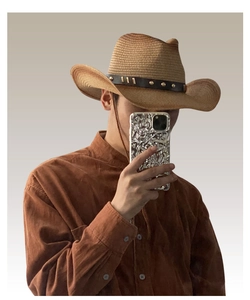 Close-up of a vintage straw cowboy hat with studded band worn by model in a selfie