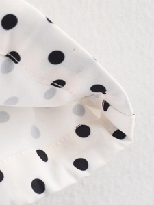 Dettaglio ravvicinato di tessuto twill bianco con pois neri e trama definita