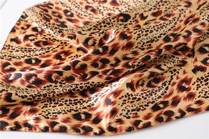 Close-up of leopard print satin scarf showing smooth texture and glossy silk fabric