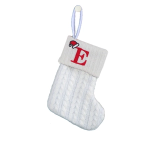Close-up of white knitted Christmas stocking featuring red embroidered letter E and hat