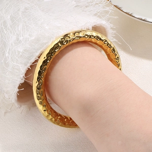 Detail of 18k gold plated stainless steel bangle with hammered texture on female wrist