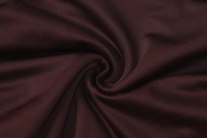Macro shot of dark burgundy pleated fabric texture showing soft knit drape and fine fibers