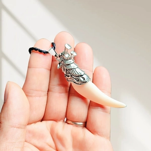 Detailed view of resin wolf tooth pendant with silver dragon head and black rope