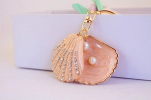Close-up of golden shell keychain with sparkling rhinestones and elegant pearls