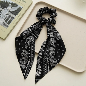 Detail of black and white paisley print scrunchie with long ribbon on a white tray