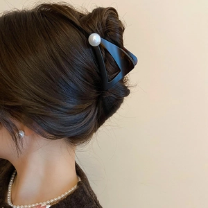 Détail d'une pince à cheveux tortue avec perle sur une coiffure relevée élégante