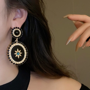 Close-up of vintage baroque gold earrings with black stones and star pattern