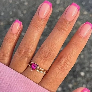 Pink heart-shaped gemstone ring with gold band and stacked pavé rings on hand