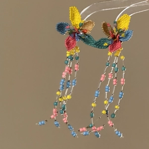Detailed view of colorful glass seed beaded flower tassel earrings in dopamine style